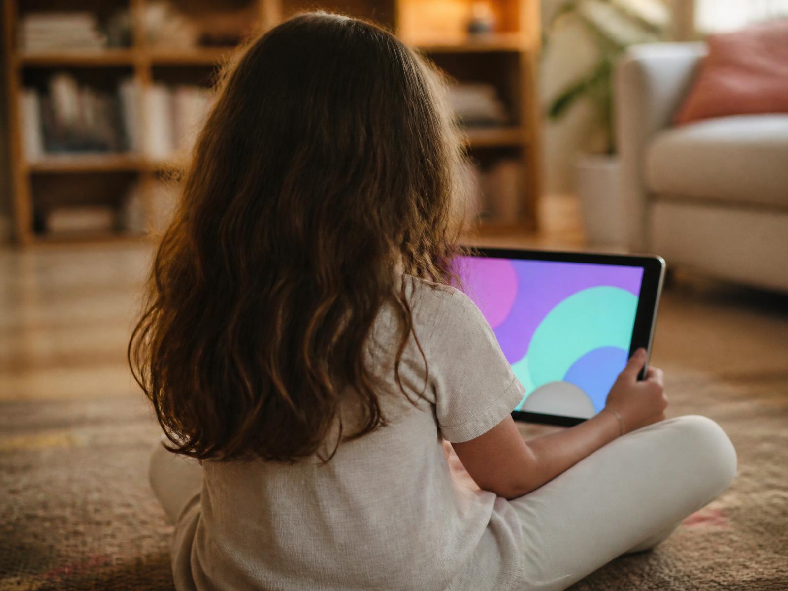 A child sitting on the floor watching calming, colourful content on a tablet